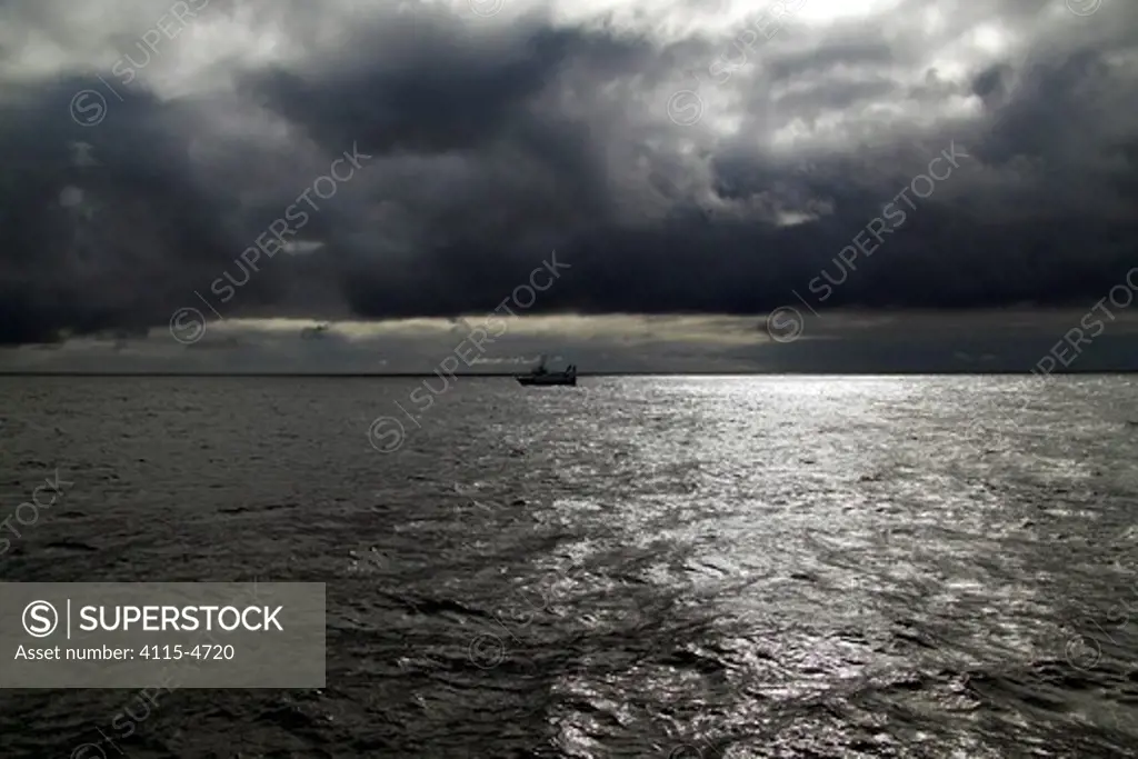 Storm clouds gathering over a trawler on the North Sea, May 2010.