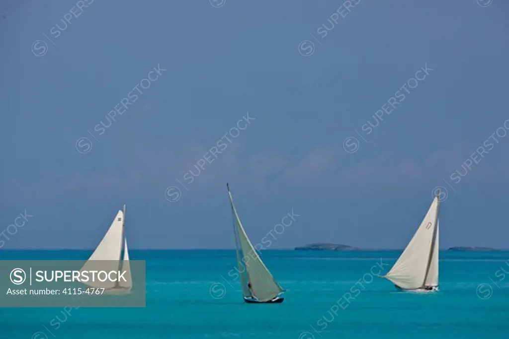 Three boats sailing on turquoise seas during the Bahamian Sloop regatta, Georgetown, Exumas, Bahamas. April 2009.