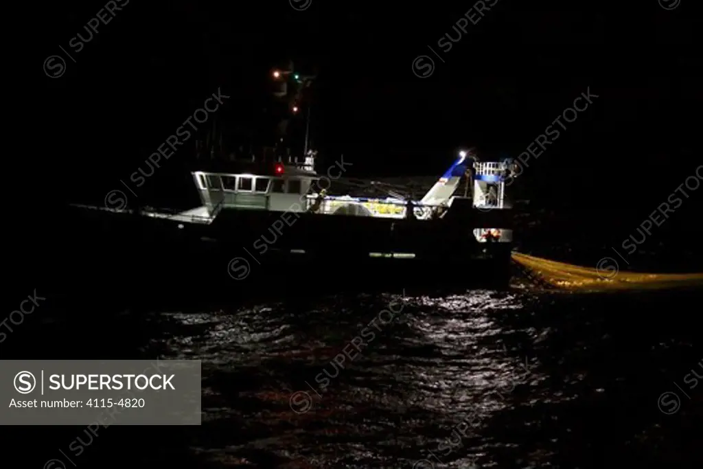 Trawler hauling net onboard during night fishing. September 2010. Property released.