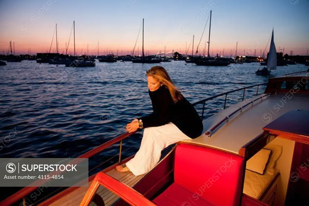 Woman relaxing on stern of luxury motorboat 'Aphrodite' in the evening. Newport, Rhode Island, USA, July 2010. Model and Property released.