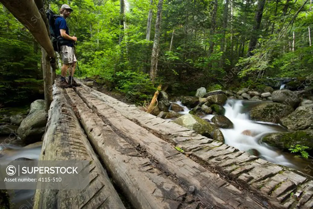 A hiker on a bridge over Gorge Brook, White Mountains, New Hampshire, USA