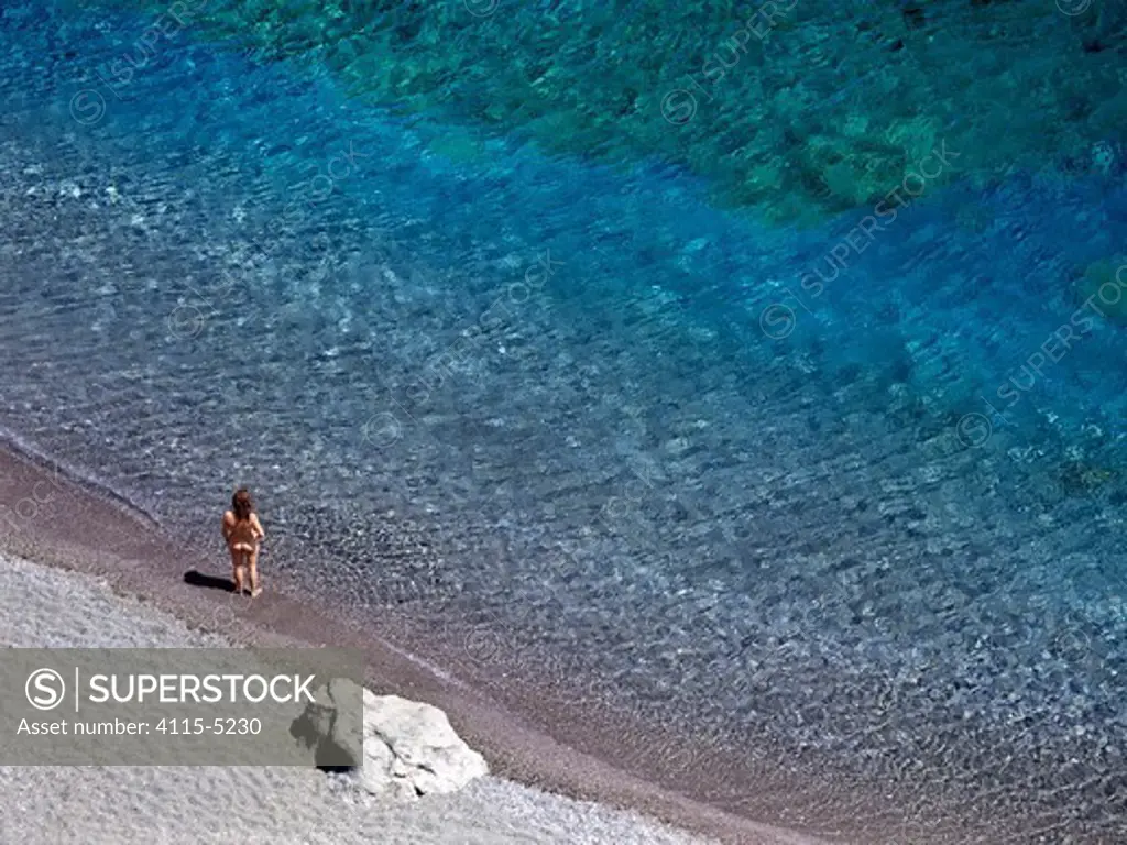A woman standing on the shore, at the corner of Preveli beach, on the South coast of Crete, Greece