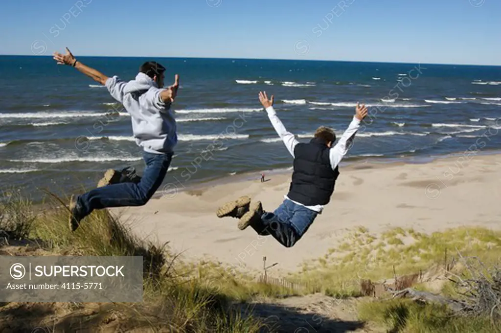 Two boys leaping off sand dunes beside Lake Michigan, Holland, Michigan, USA, model released, October 2004