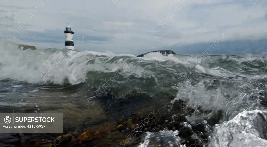 A low angle view of Penmon lighthouse with waves crashing towards the camera, Anglesey, Wales, October 2009.