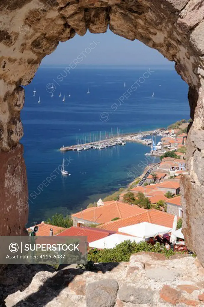 Molyvos / Mithymna harbour, viewed through an arched window of the 13th century castle above the town, with sailing yachts gathering for the Aegean regatta offshore. Lesbos / Lesvos, Greece, August 2010