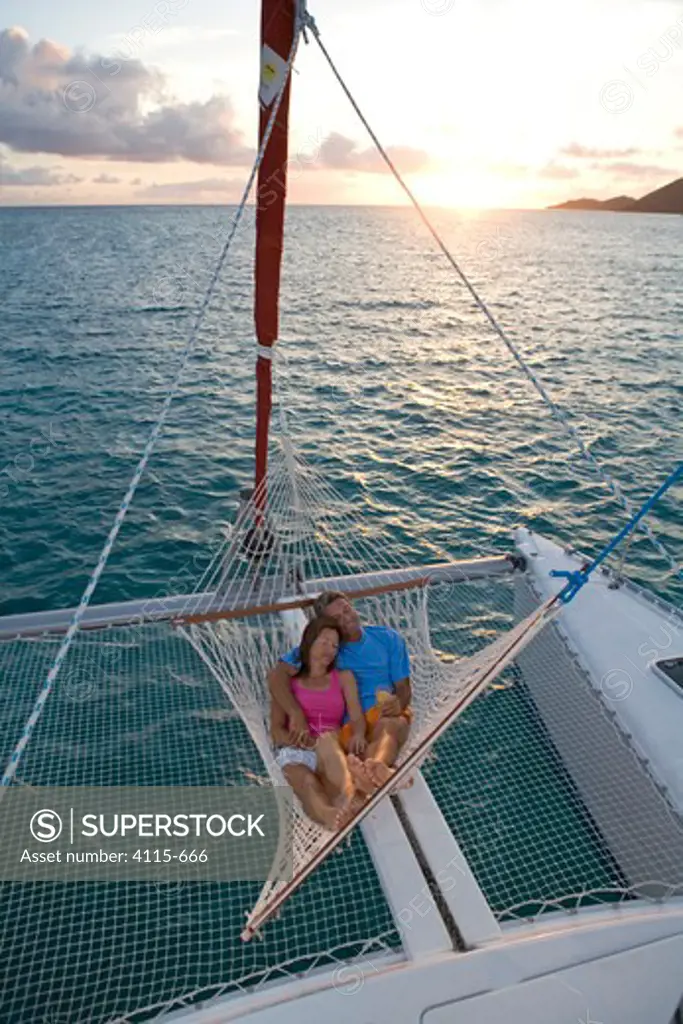 Couple relaxing in hammock on the stern of a Sunsail Lagoon 410 catamaran at sunset. British Virgin Islands, April 2006