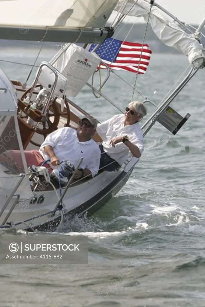 Two men sitting in the cockpit on the leeward side of a Shannon 39 yacht near East Hampton, New York. June 2005.