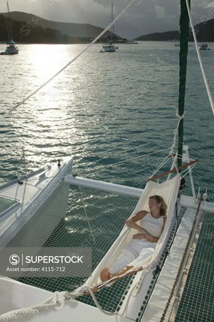 Woman relaxing in a hammock over trampoline of Lagoon 470 Sunsail charter catamaran 'KooLau', British Virgin Islands, January 2004.