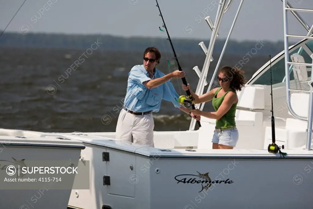 Couple with fishing rod on aftdeck of a sportsfisher.
