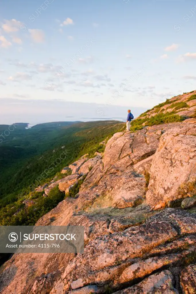 A lone hiker near the summit of Cadillac Mountain at dawn, Acadia National Park, Maine, USA