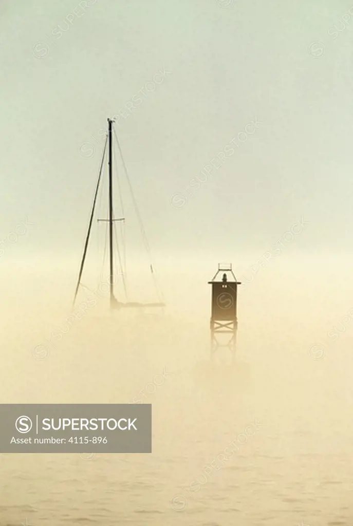 A mast and bell buoy emerging from the fog in the waters off Somes Sound, Maine, USA.