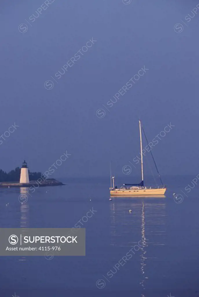 A yacht anchored near Goat Island Lighthouse on a calm morning, Newport, Rhode Island, USA.