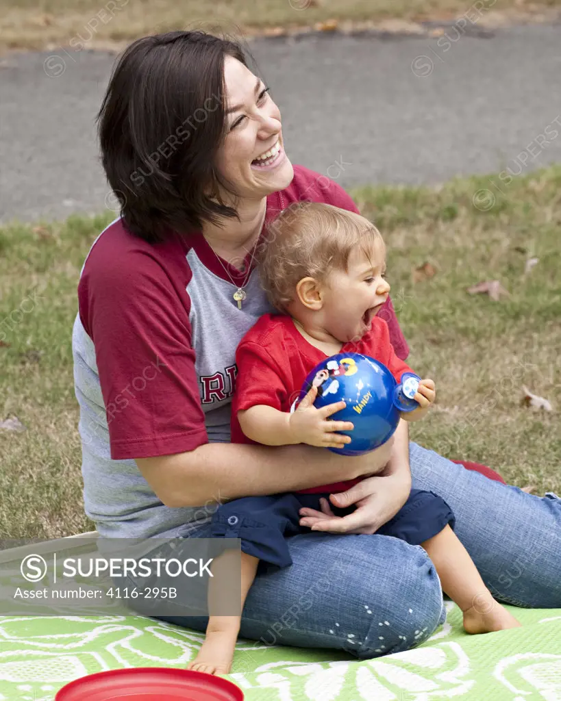USA, Arkansas, Mother with baby boy sitting on lawn, laughing