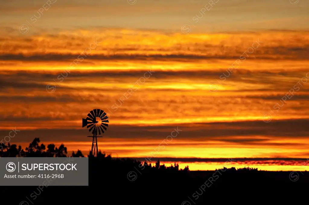 USA, New Mexico, Silhouette of wind mill against golden sky at dawn