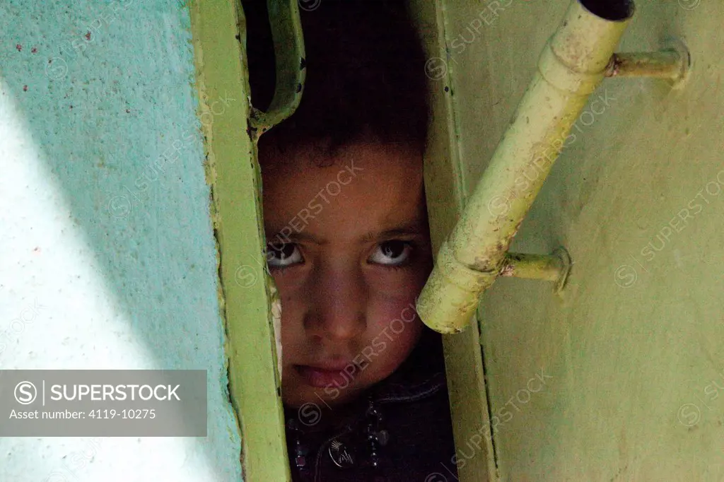 Photograph of a little Morrocan girl glancing from the front door of her house in Setti Fatma, Morroco