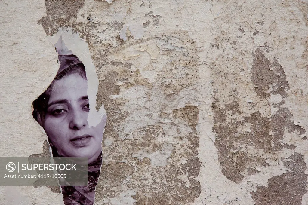 Abstract view of a torn monochromatic photograph of a woman glued to a wall in Essaouira, Morocco
