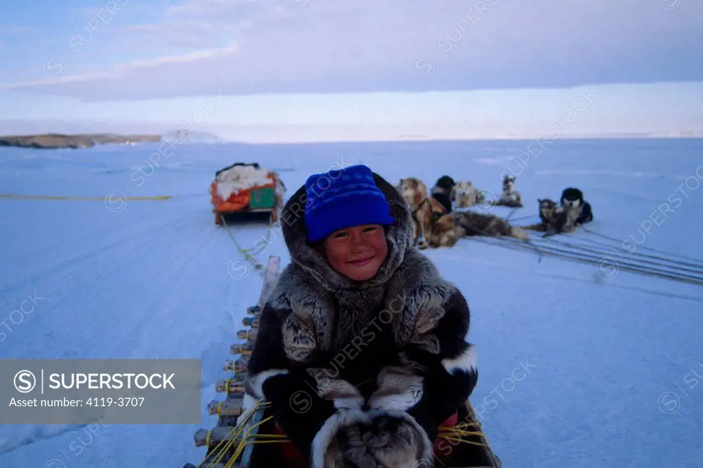 Photograph of a young Eskimo boy sitting in a sled in Baffin Canada