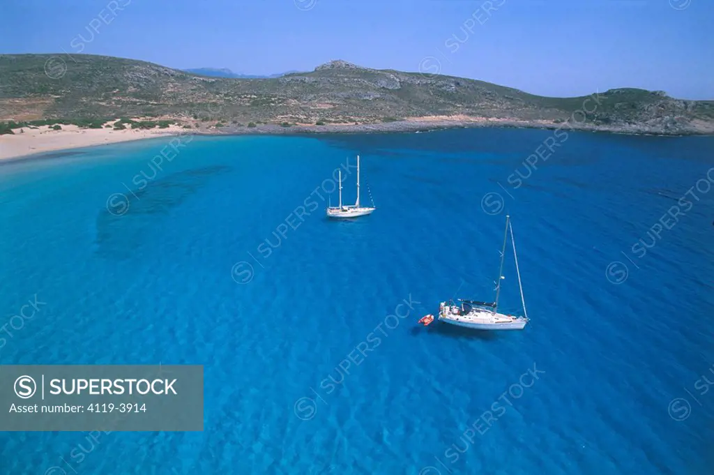 Aerial photograph of a couple of Yachts anchor in a blue lagune of the Greek island of Elafonisos