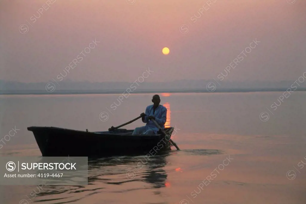 Photograph of an Indian man rowing a boat on the Ganges river