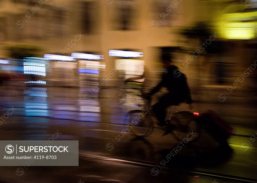man riding his bicycles and carring a suitcase at night in sevilla, spain