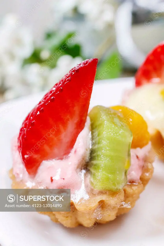 Beautiful cupcakes decorated with fresh fruits: strawberry, peach, kiwi