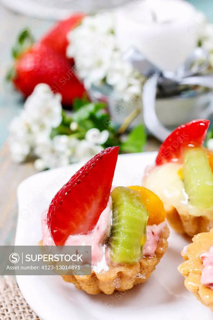 Beautiful cupcakes decorated with fresh fruits: strawberry, peach, kiwi