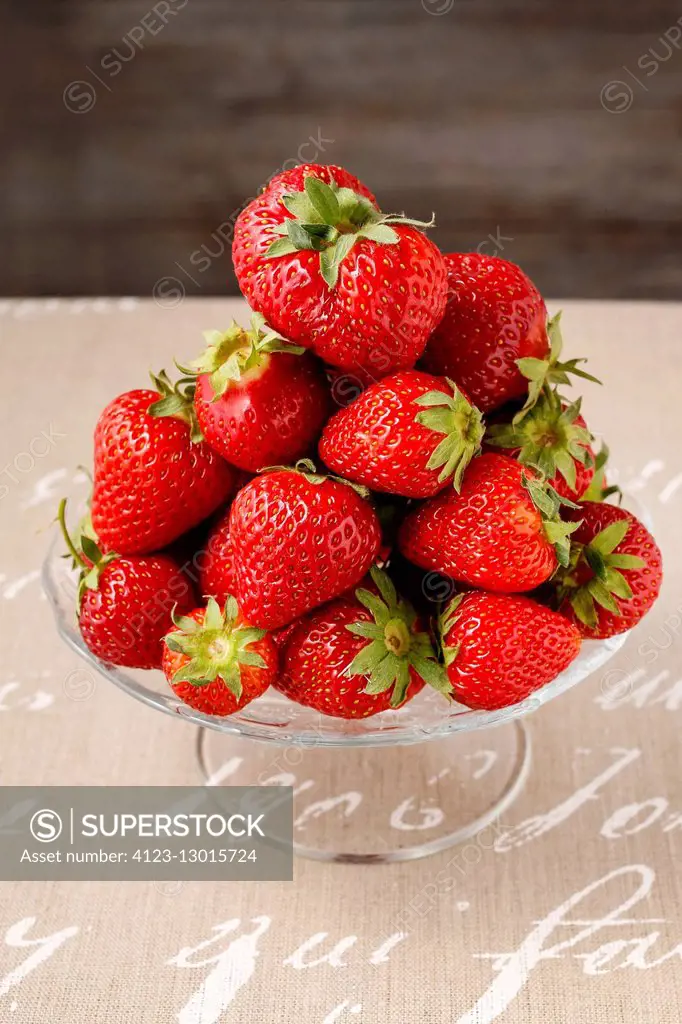 Pile of strawberries on glass cake stand. Healthy food