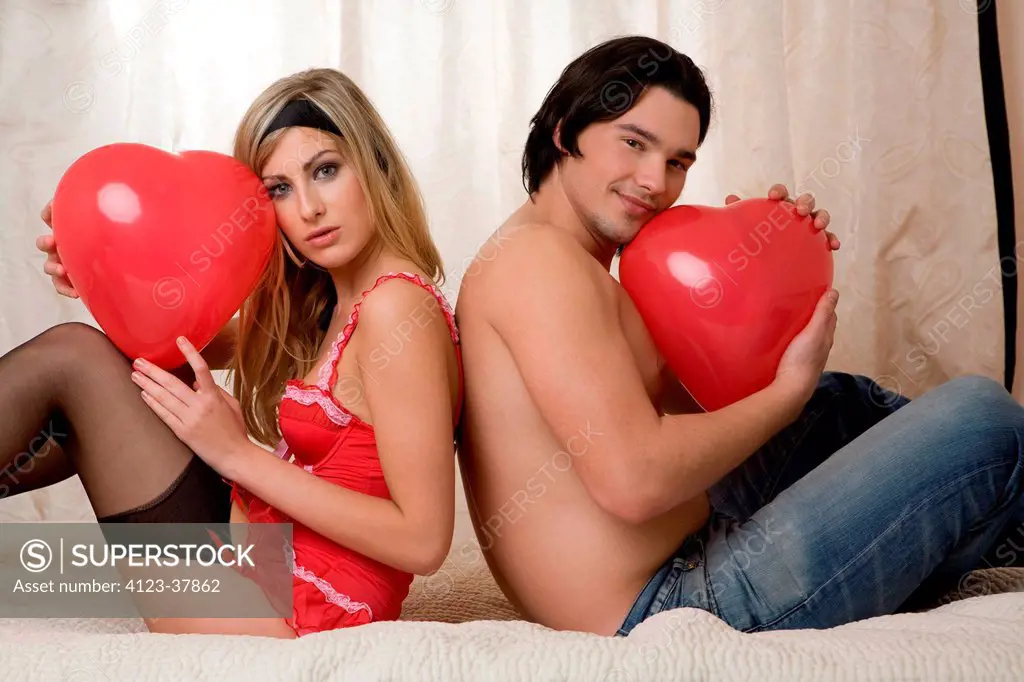 Couple in the bedroom holding heart_shaped balloon