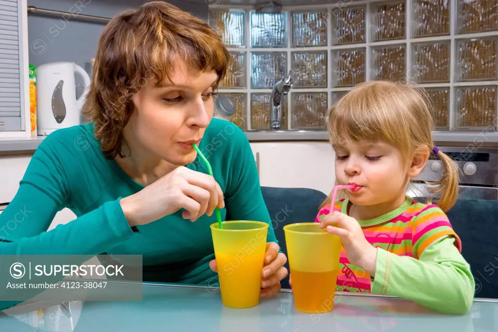 Mother and her daughter drinking juice with sippers.