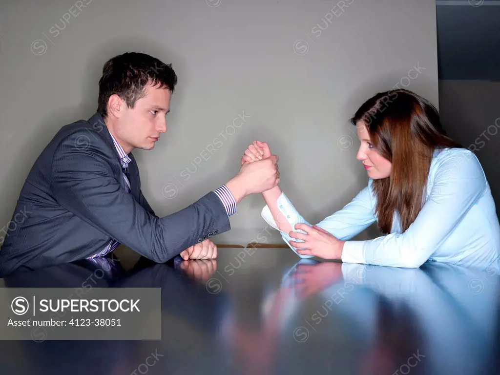 Woman and man armwrestling in the office.