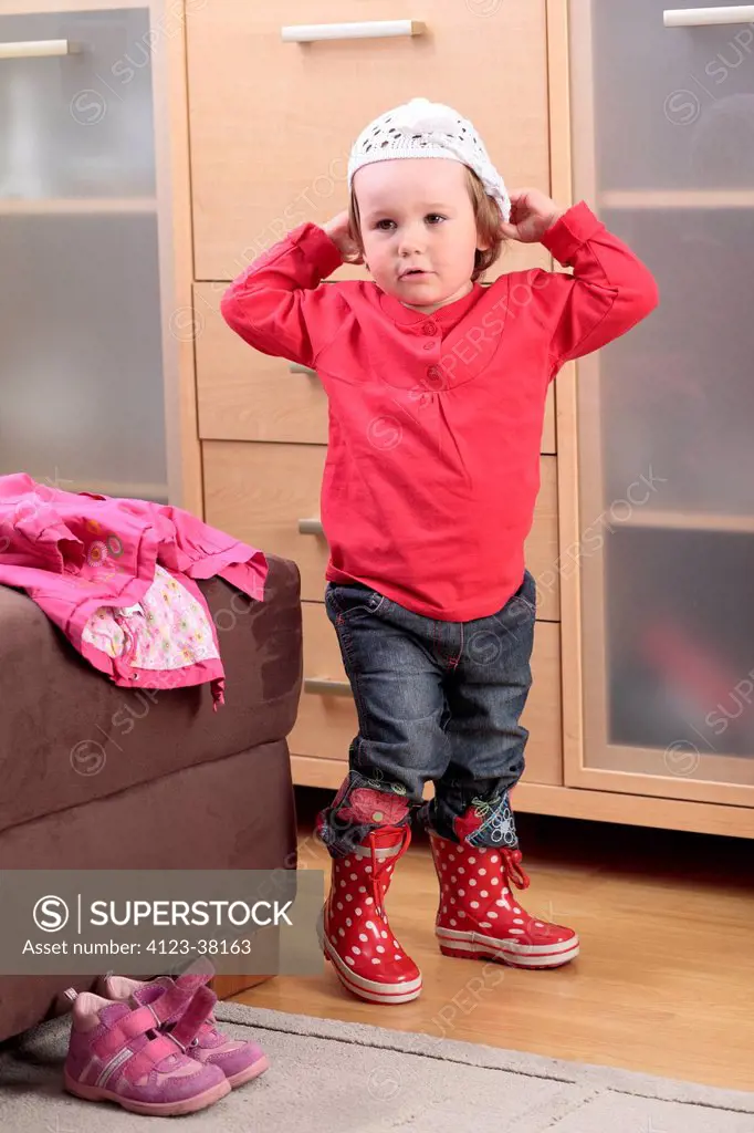Little girl dressing herself at home.