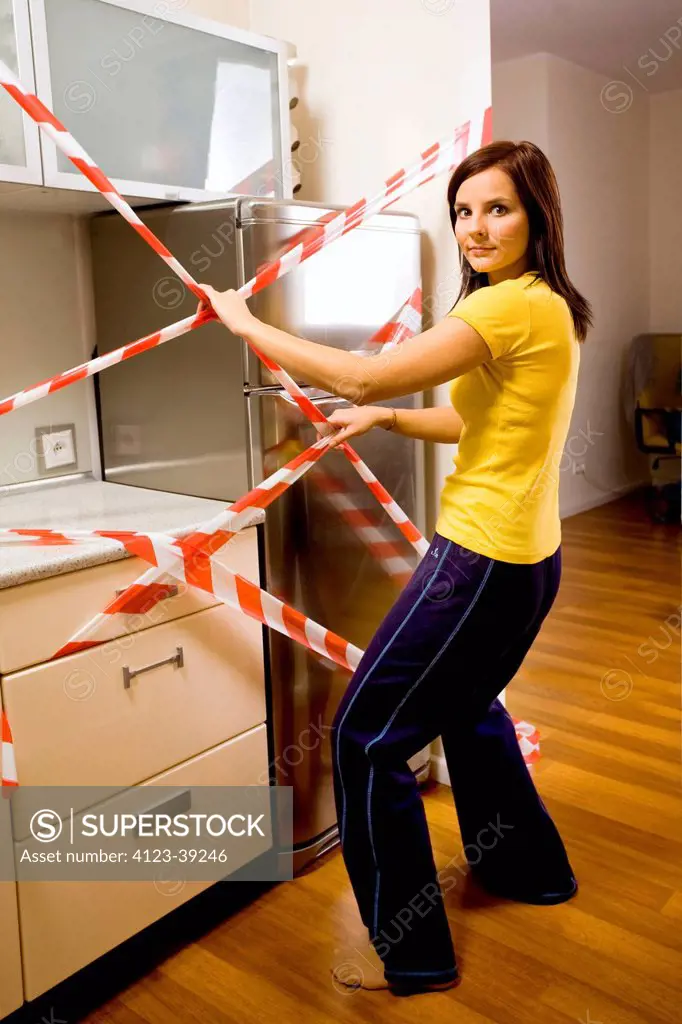 Young woman trying to open the fridge.