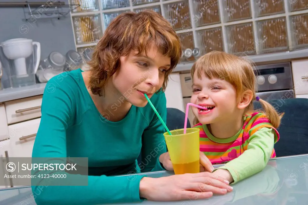 Mother and her daughter drinking juice with sippers.