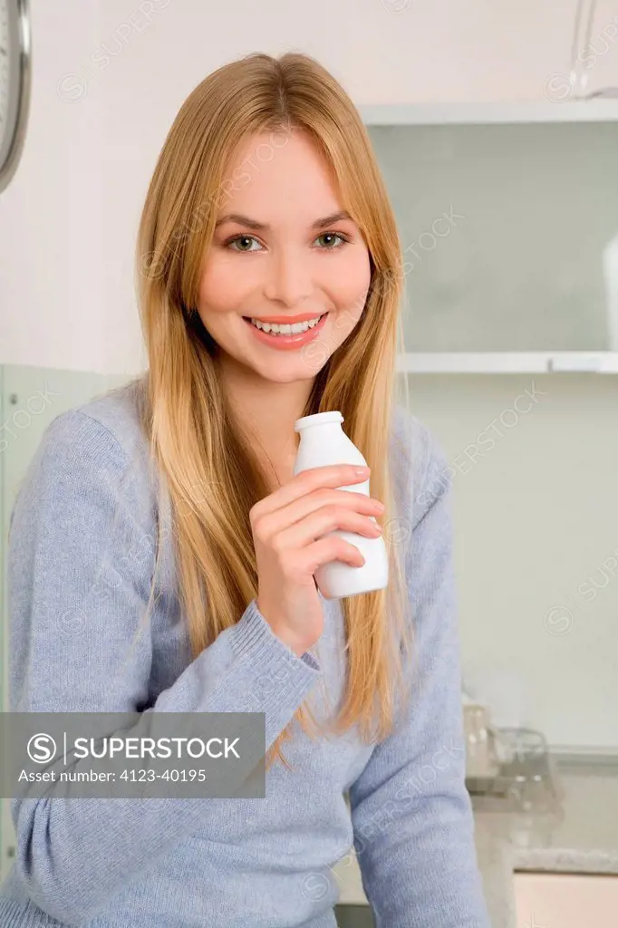 Young woman in the kitchen while drinking yoghurt
