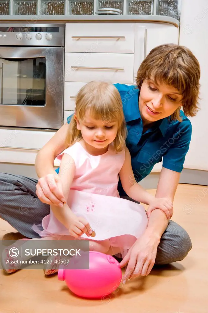 Mother and daughter putting coins into piggy bank.