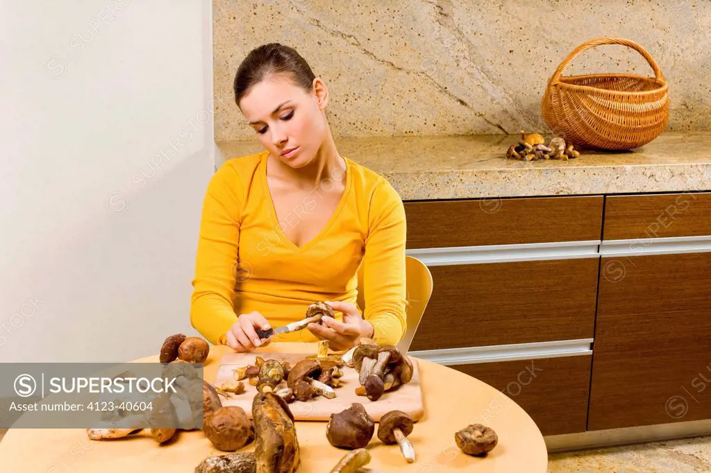 Young woman peeling and cutting mushrooms.