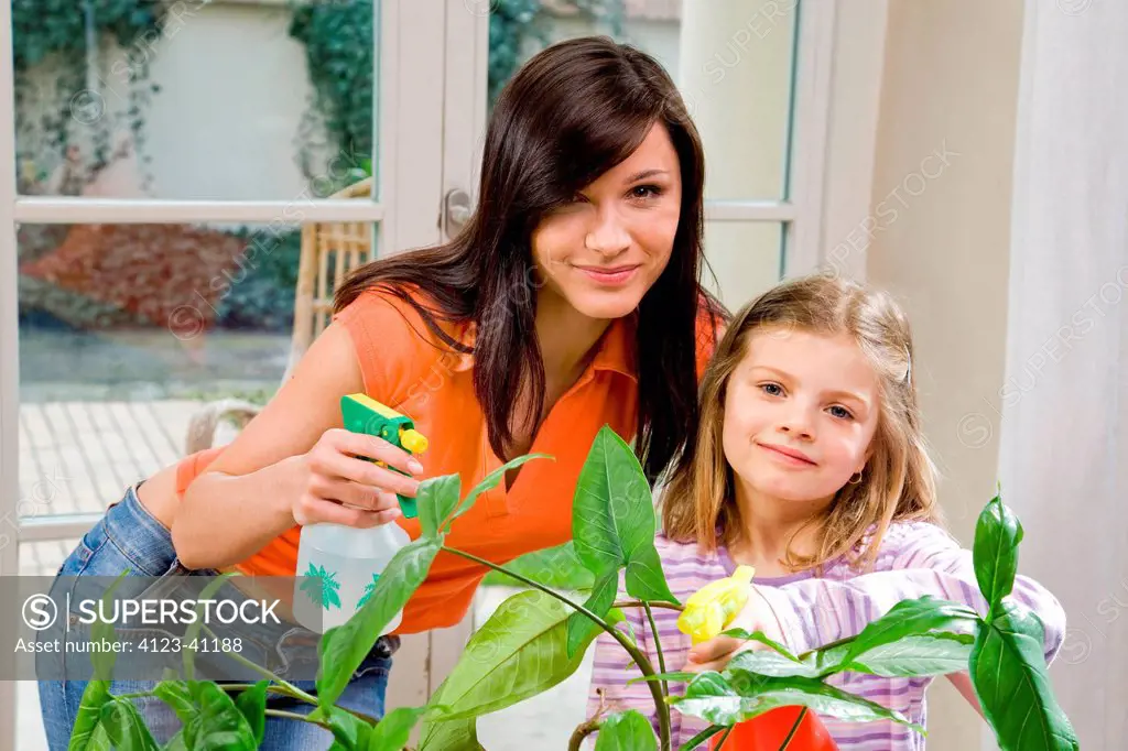 Woman and girl watering plants.