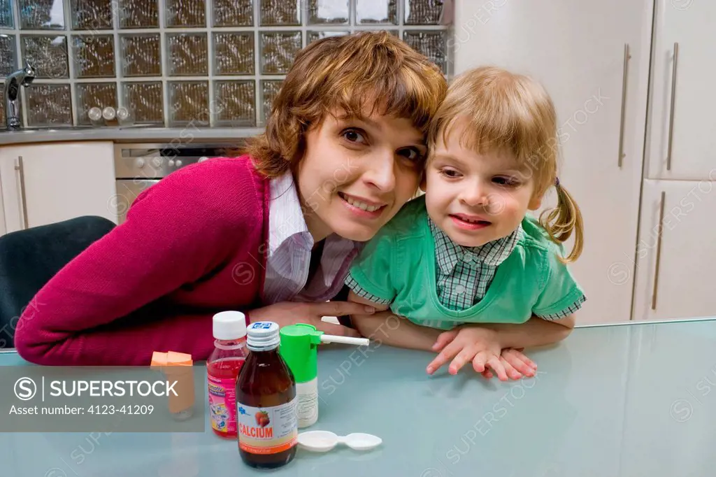 Mother giving medicine to her daughter.