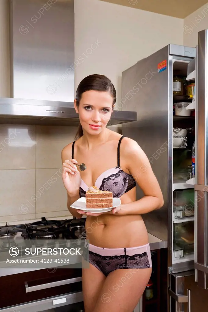 Woman in her underwear eating a cake. - SuperStock