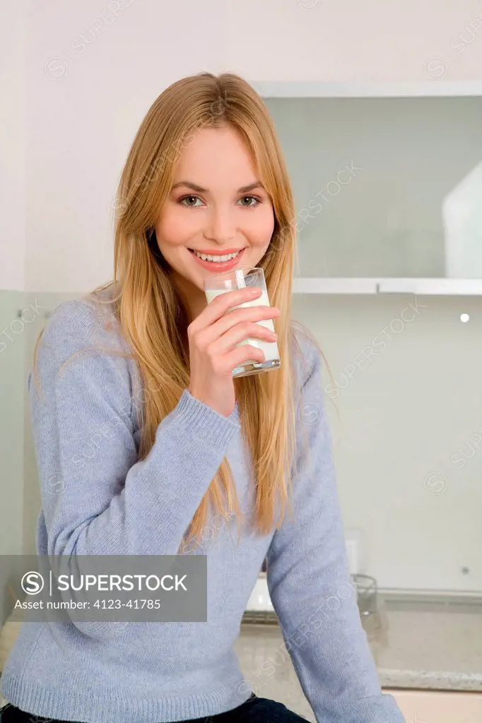 Young woman in the kitchen while drinking milk