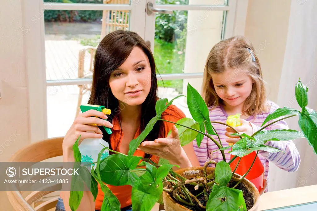 Woman and girl watering plants.