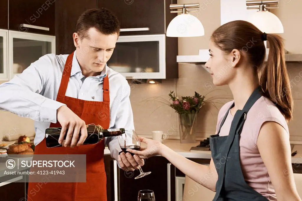 Young couple drinking wine while preparing meal