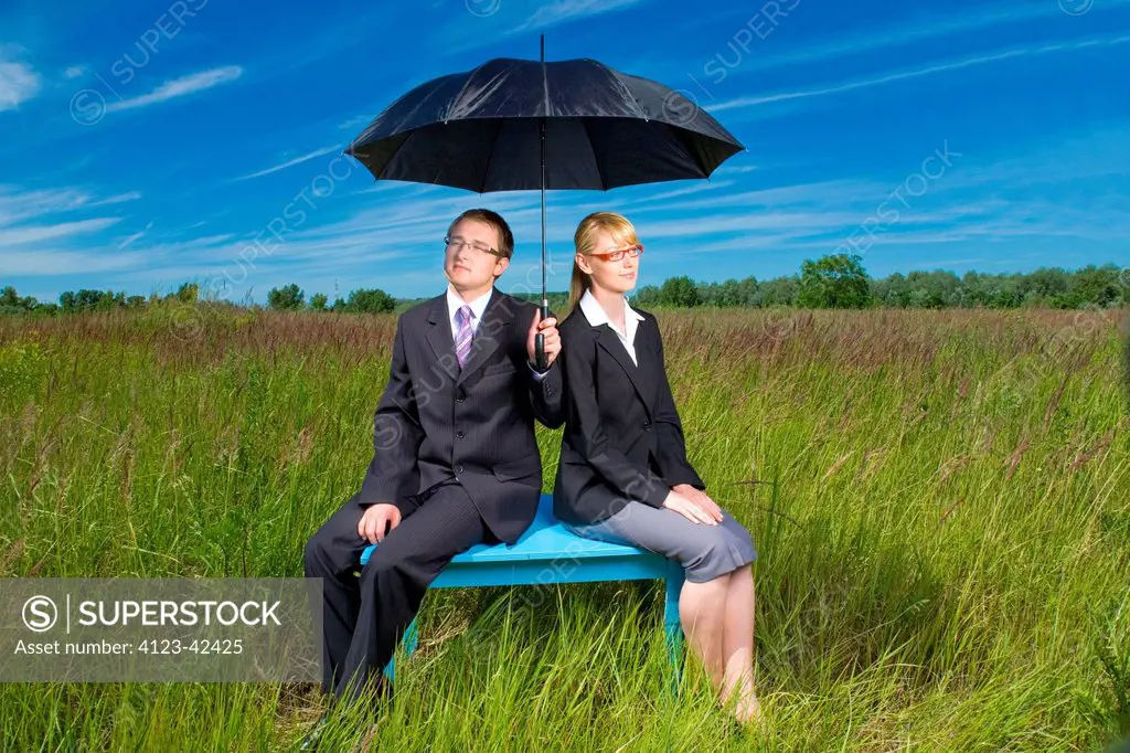 Young people on a meadow with umbrella.