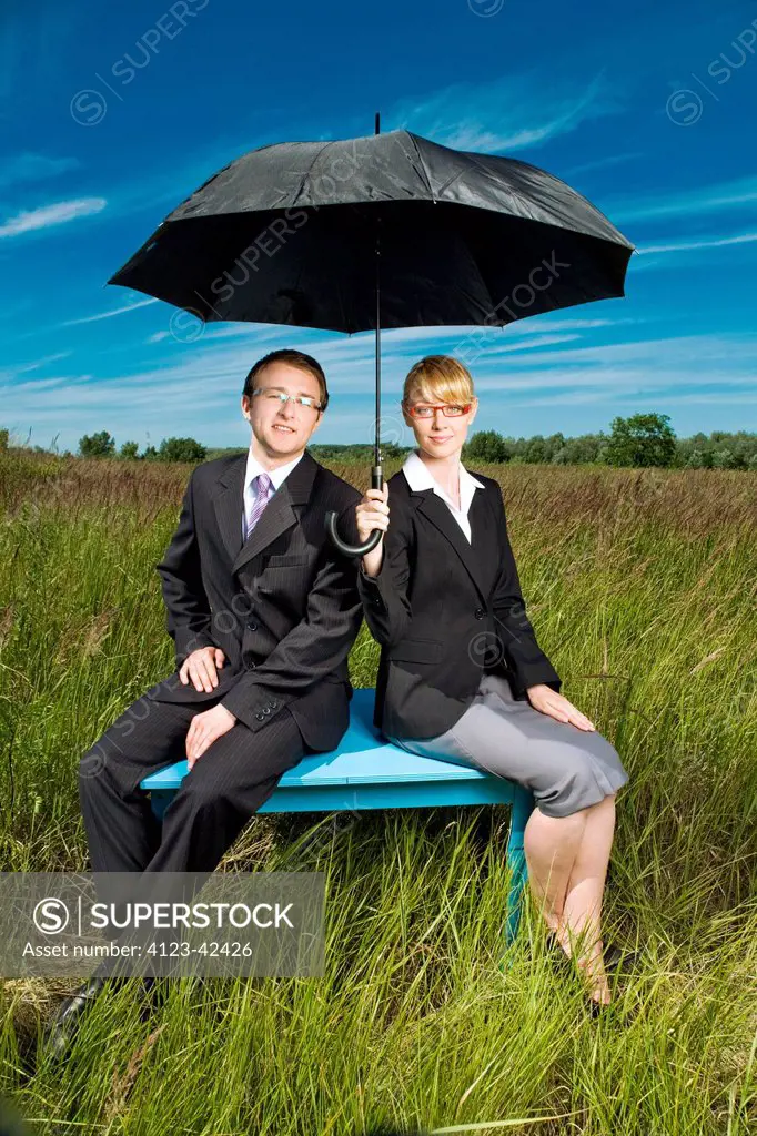 Young people on a meadow with umbrella.