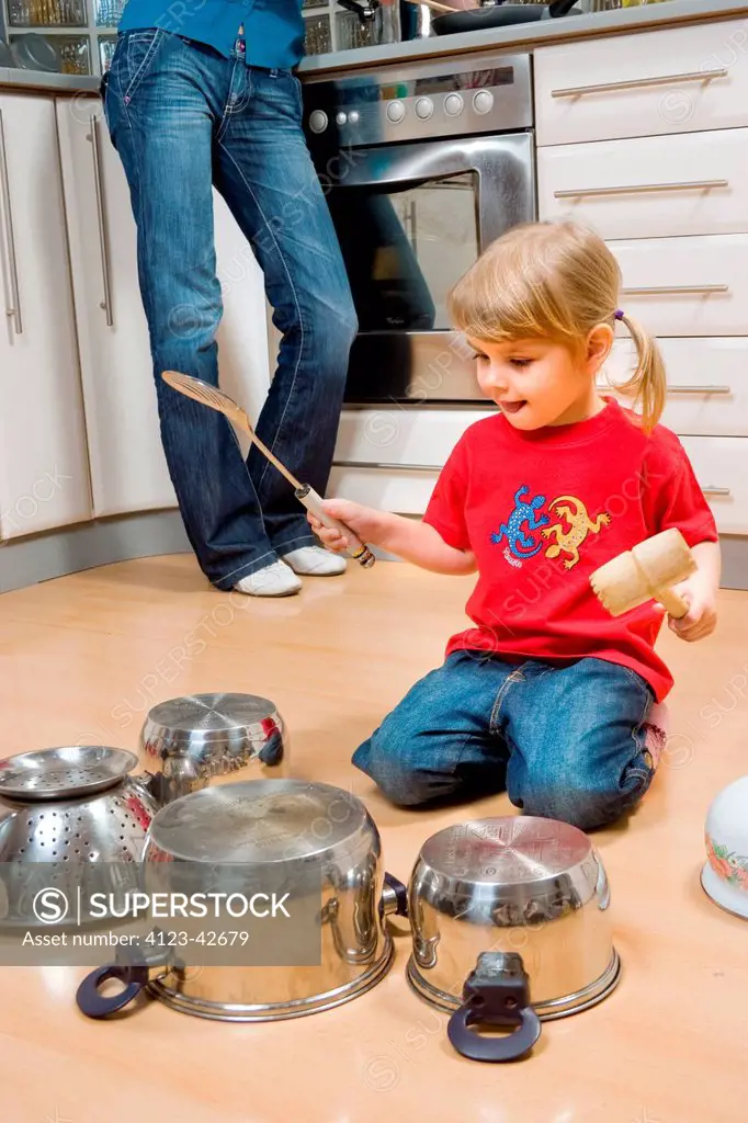 Girl drumming on pots with spatula.