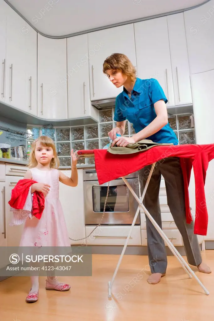 Woman ironing and looking after her daughter.