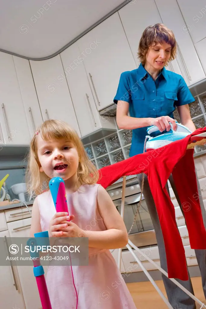 Woman ironing and looking after her daughter.