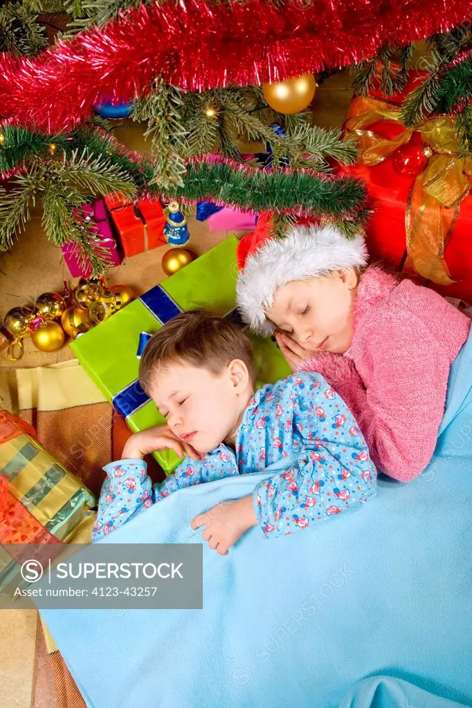 Children sleeping under the Christmas tree.