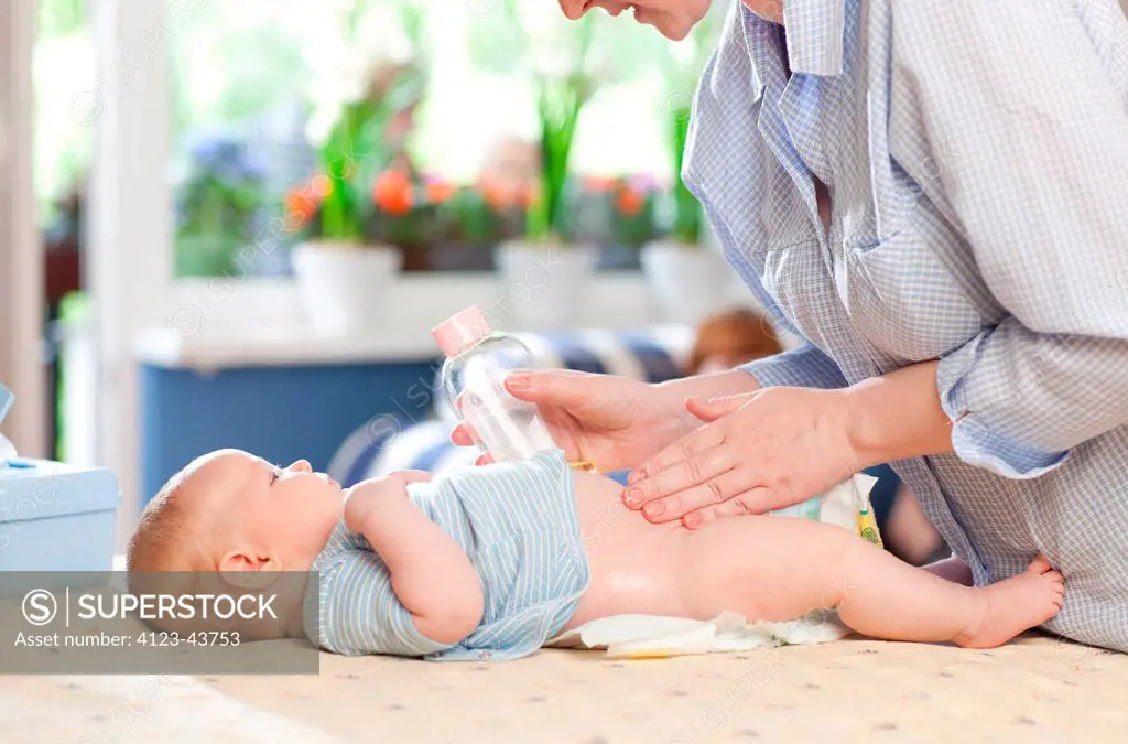 Mother changing her baby's nappy on nursery table.