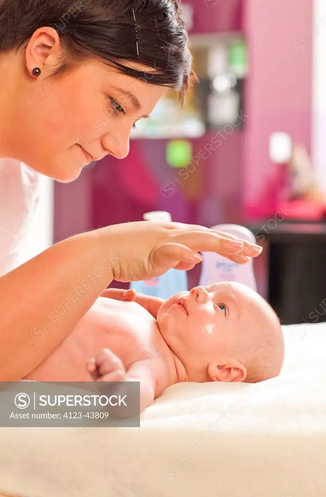 Mother applying cream to her baby's body.